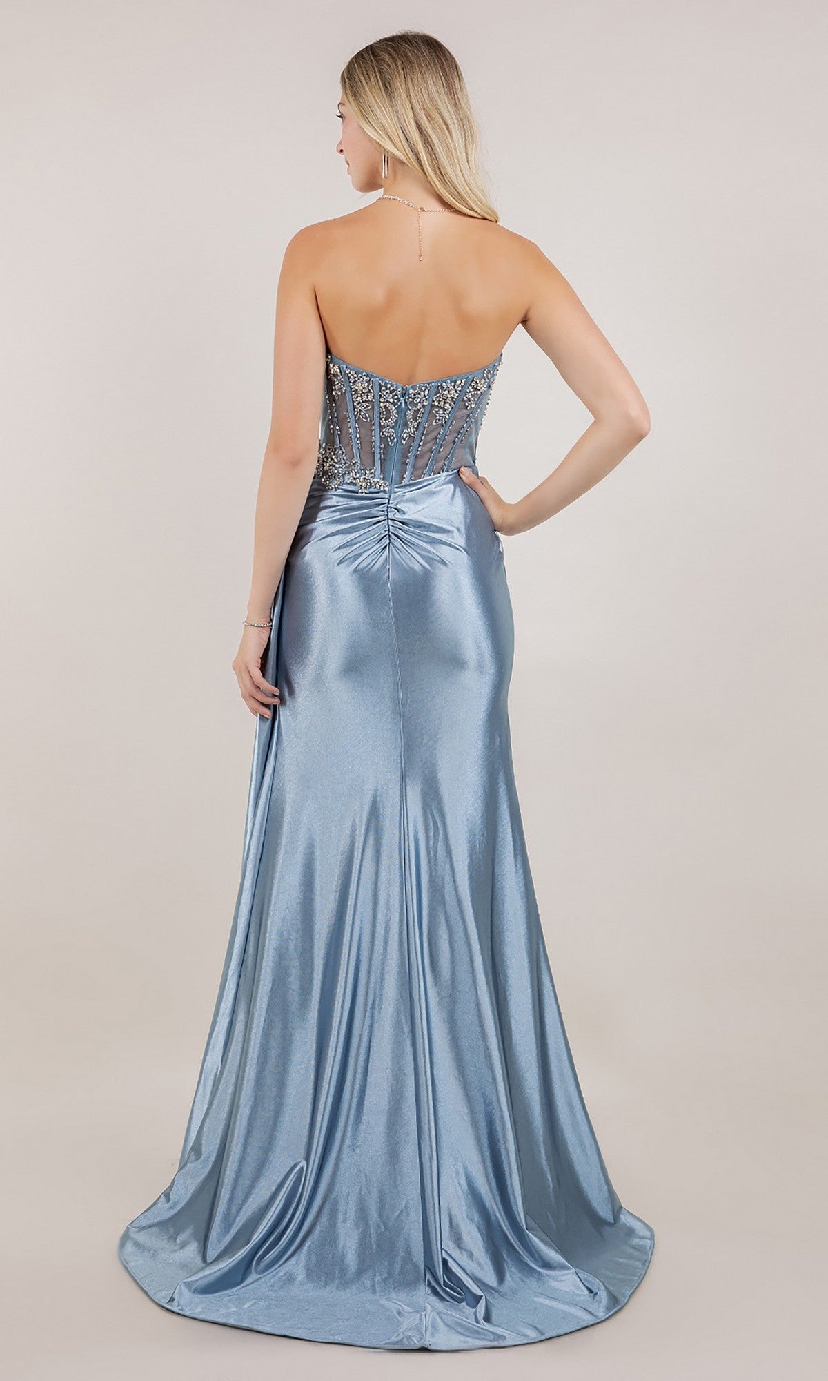 A woman faces away wearing the Cinderella Couture 8511J, a long prom dress featuring a strapless light blue satin skirt and a beaded sheer bodice with crystal beadwork.